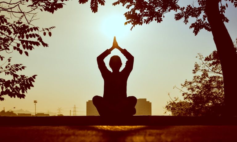 Person meditating outdoors surrounded by trees - meditation in Bracknell in harmony with nature